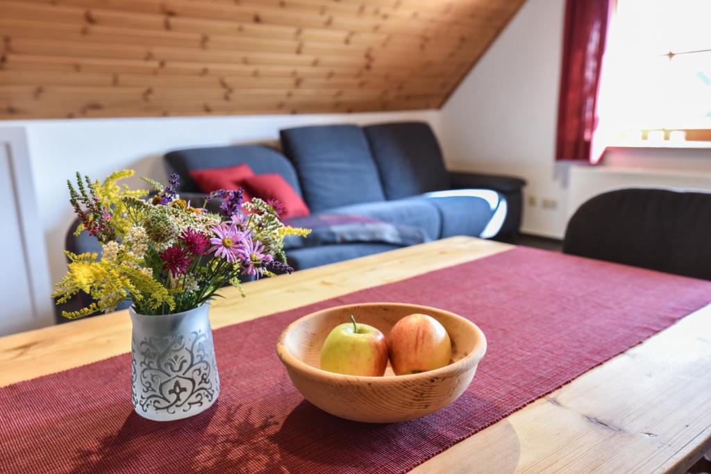 un bol de pommes et un vase de fleurs sur une table dans l'établissement Ferienwohnung Waldblick, à Kleinsteinhausen