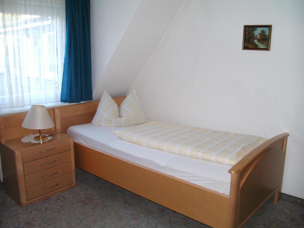 a bedroom with a bed with a nightstand and a window at Pension Gastreich in Lennestadt