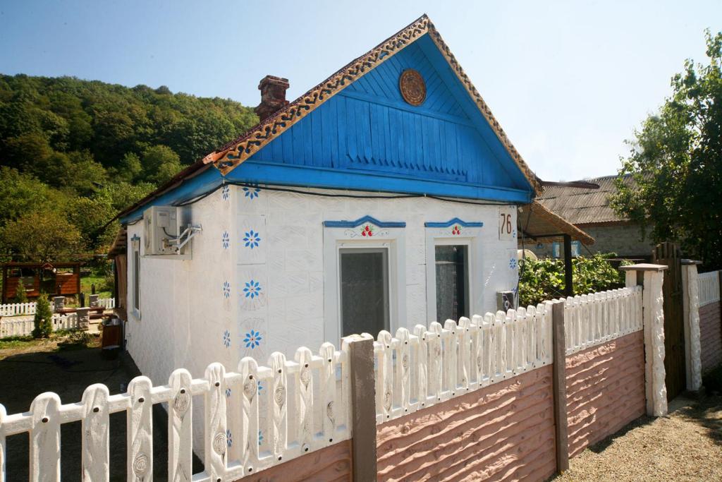 a small white house with a blue roof behind a fence at На опушке in Tul'skiy