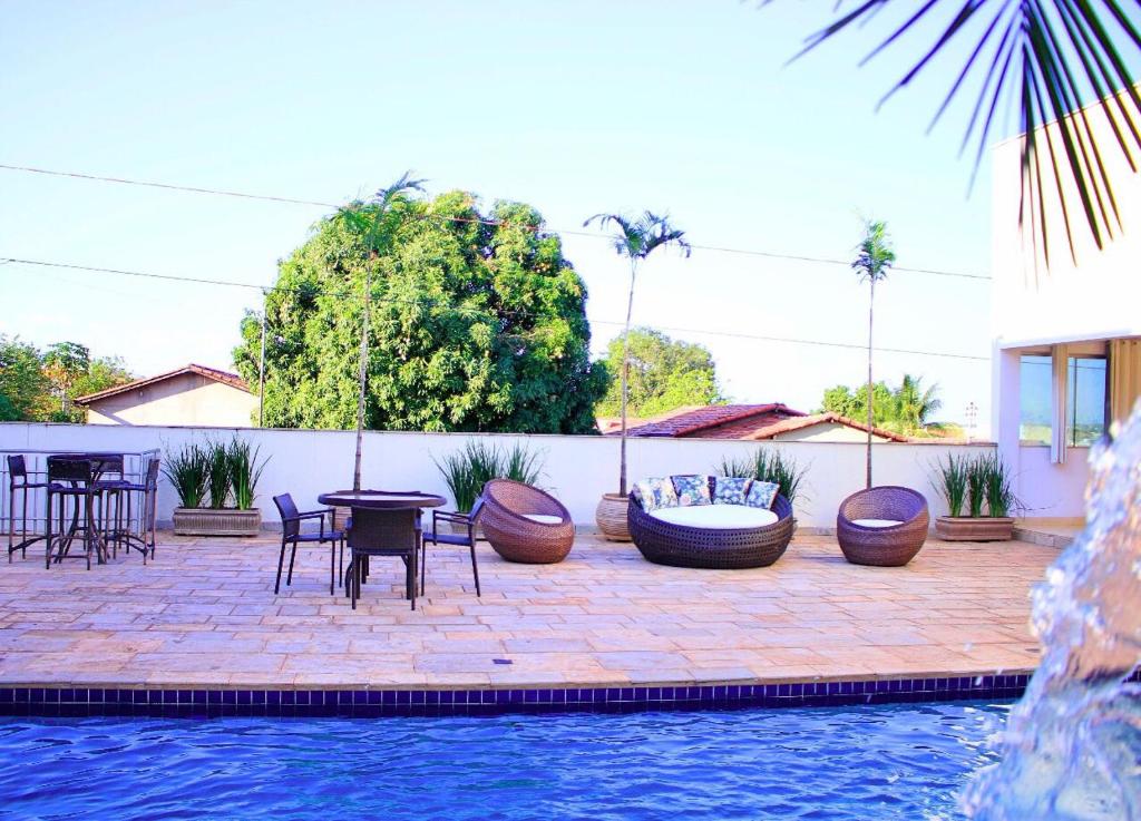 a patio with tables and chairs next to a pool at Mais Hotel in Araguaína