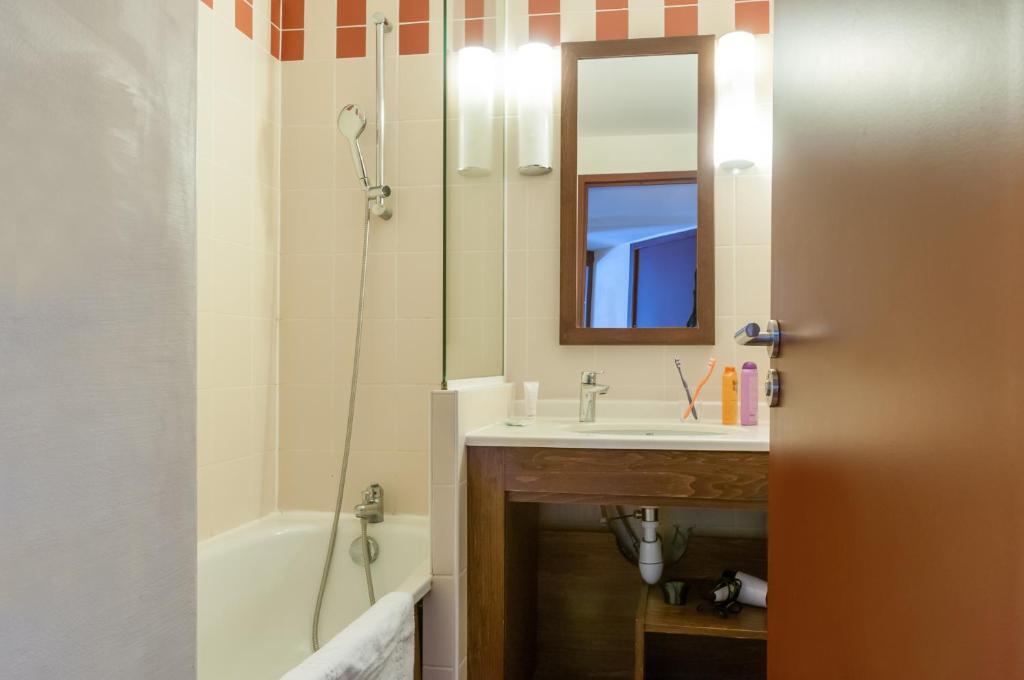 a bathroom with a sink and a tub and a mirror at Résidence Pierre & Vacances Le Belmont in Arc 1800