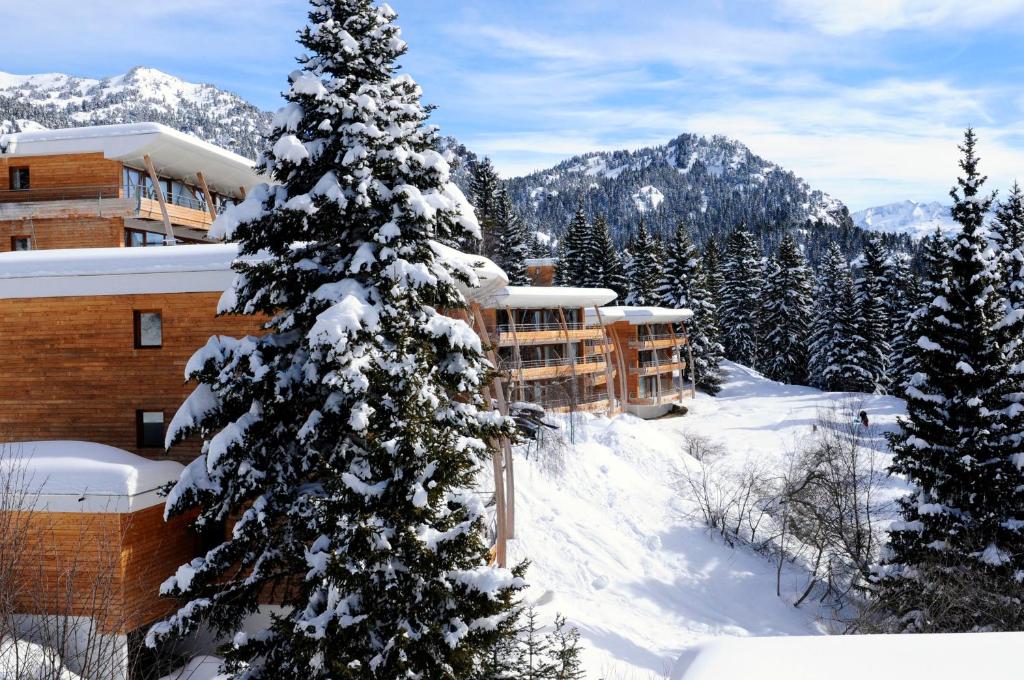 a snow covered christmas tree in front of a hotel at Résidence Les Villages du Bachat in Chamrousse