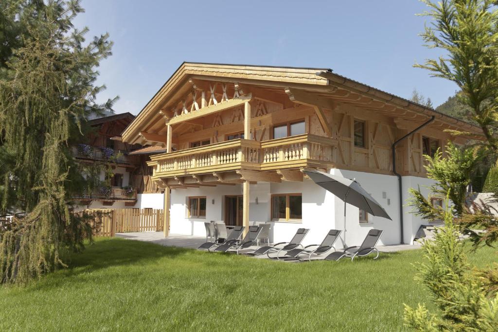 une maison avec un balcon et des chaises dans la cour dans l'établissement Alpenresidenz Ötztal, à Oetz