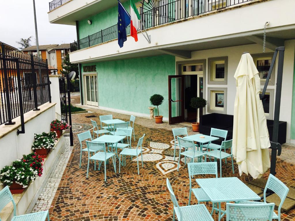 een patio met tafels en stoelen en een parasol bij Hotel San Berardo in Pescina