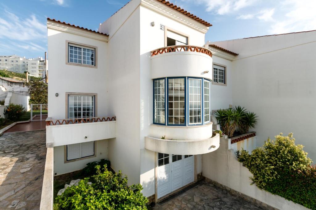 a white house with balconies and plants at Casa das Conchas in Ericeira