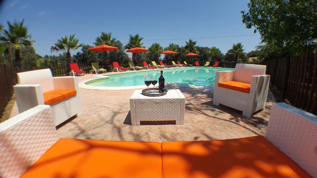 a pool with a table and chairs and a bottle of wine at Il Noceto in Monte San Giusto