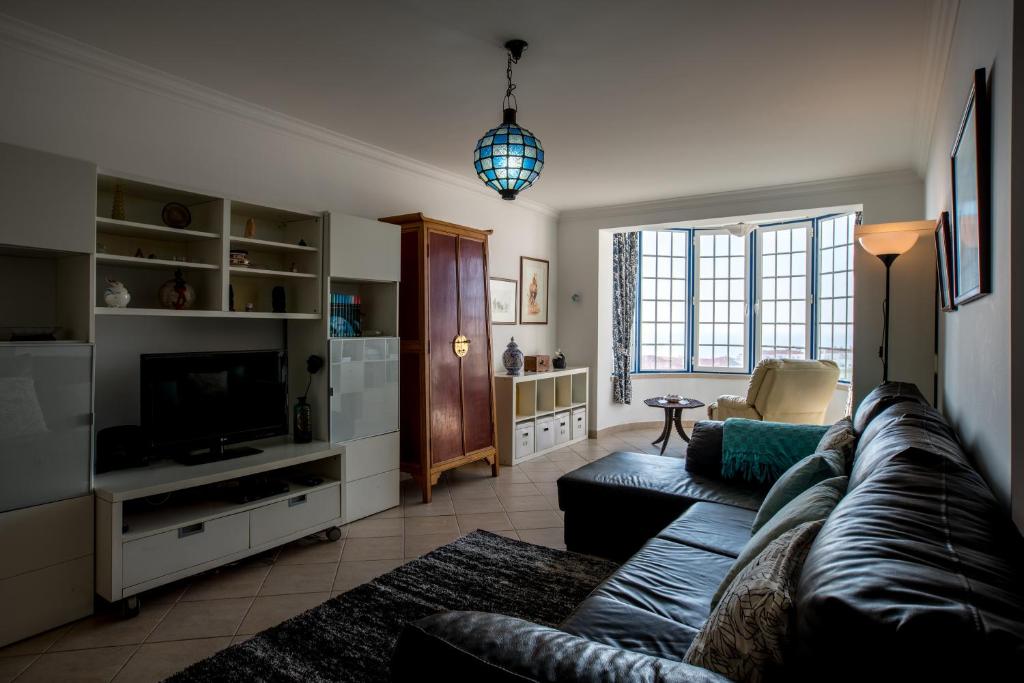 a living room with a couch and a television at Casa das Conchas in Ericeira