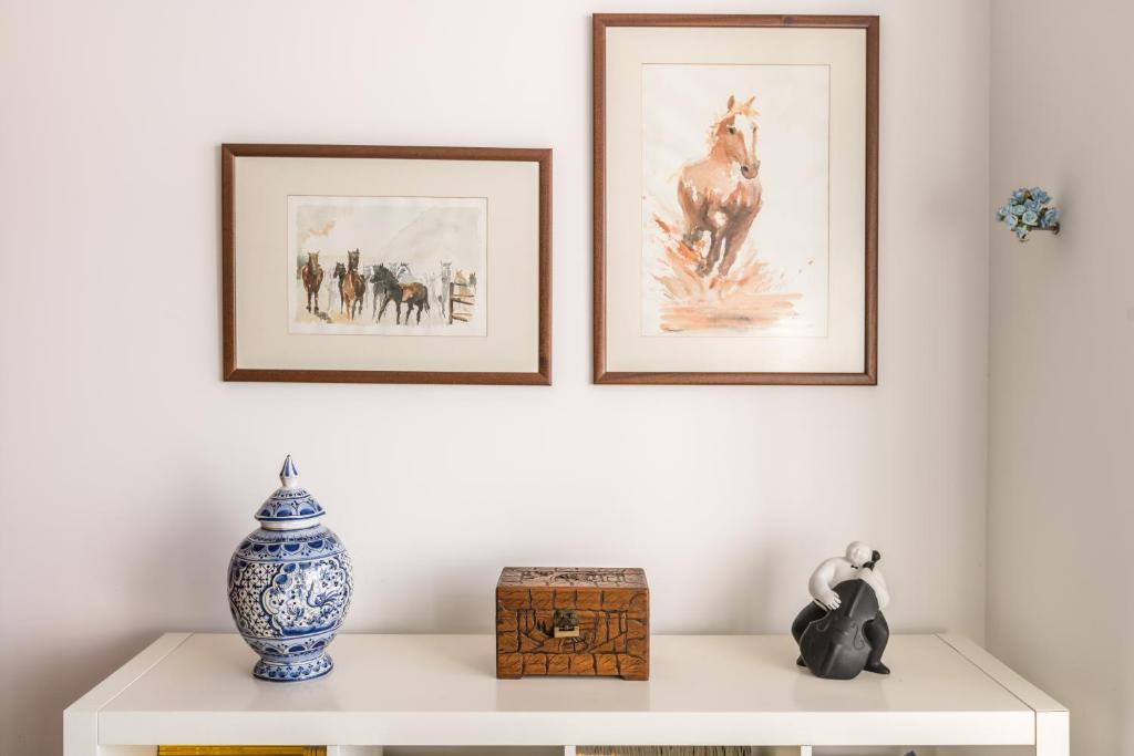 a white table with two framed pictures on a wall at Casa das Conchas in Ericeira