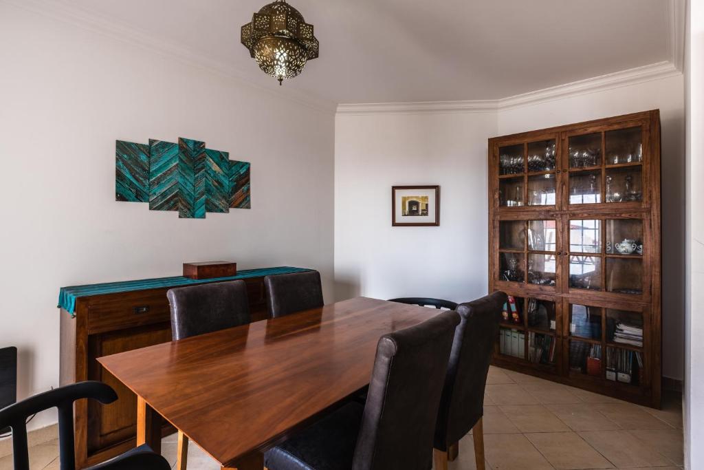 a dining room with a wooden table and chairs at Casa das Conchas in Ericeira