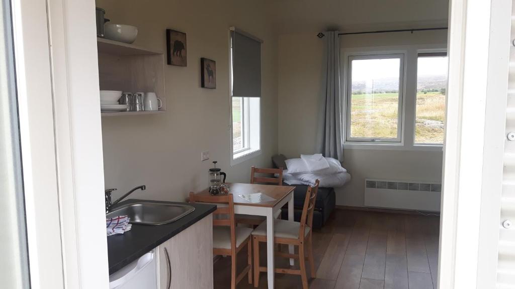 a kitchen with a sink and a table and a window at Hjartarstaðir Guesthouse in Eiðar