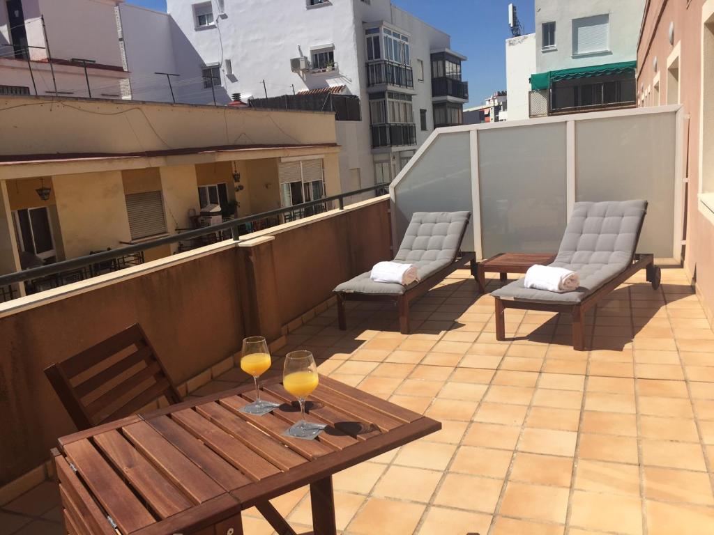 a balcony with two chairs and a table and wine glasses at Zenit Málaga in Málaga