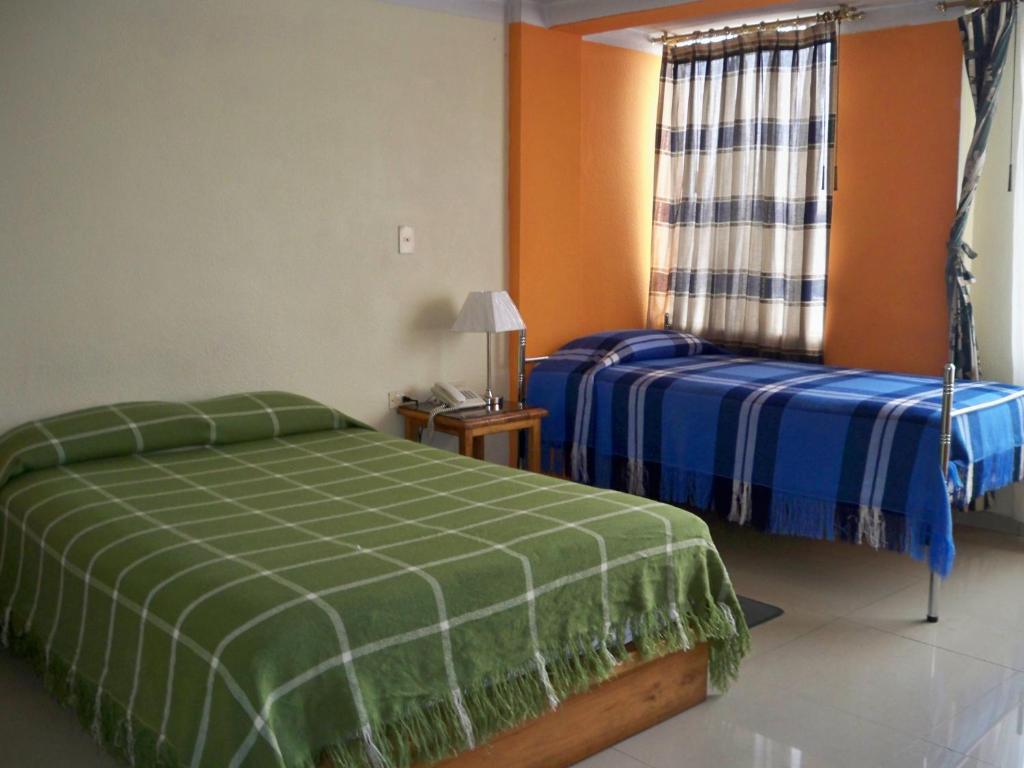 a bedroom with two beds and a window at Las Garzas Alojamiento in Ibarra