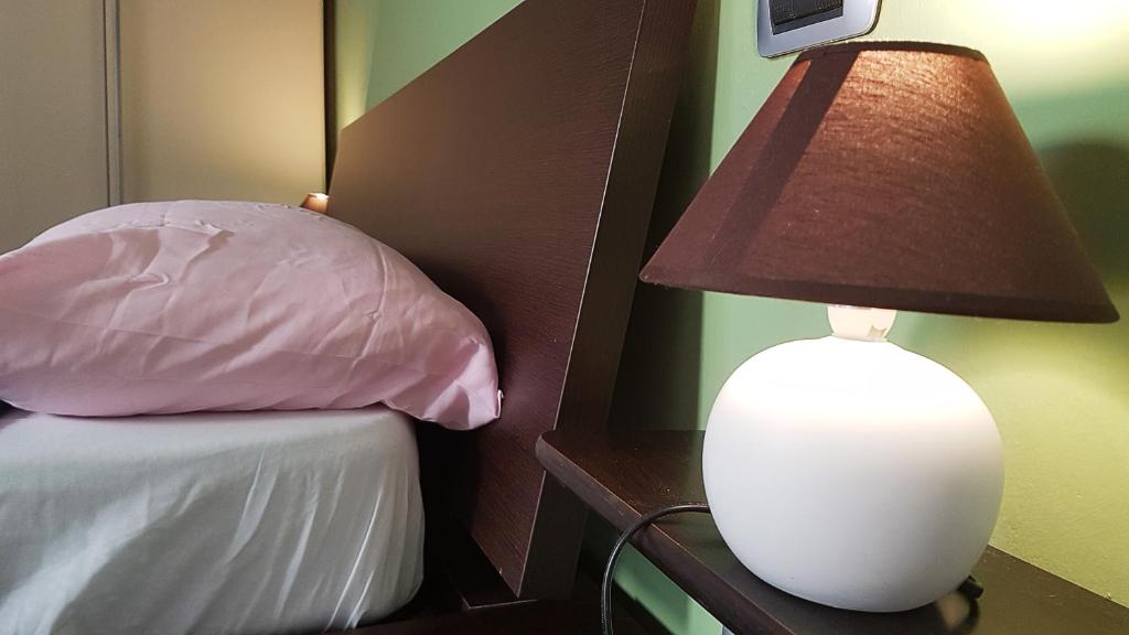 una lampada su un tavolo accanto a un letto con cuscino di S. Stefano in Pane House a Firenze