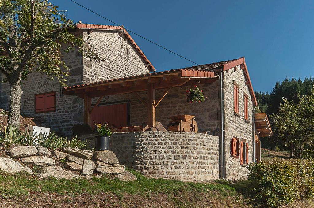 Cette petite maison en pierre est dotée d'un mur en briques. dans l'établissement Gîte " Orée des bois", à Vertolaye