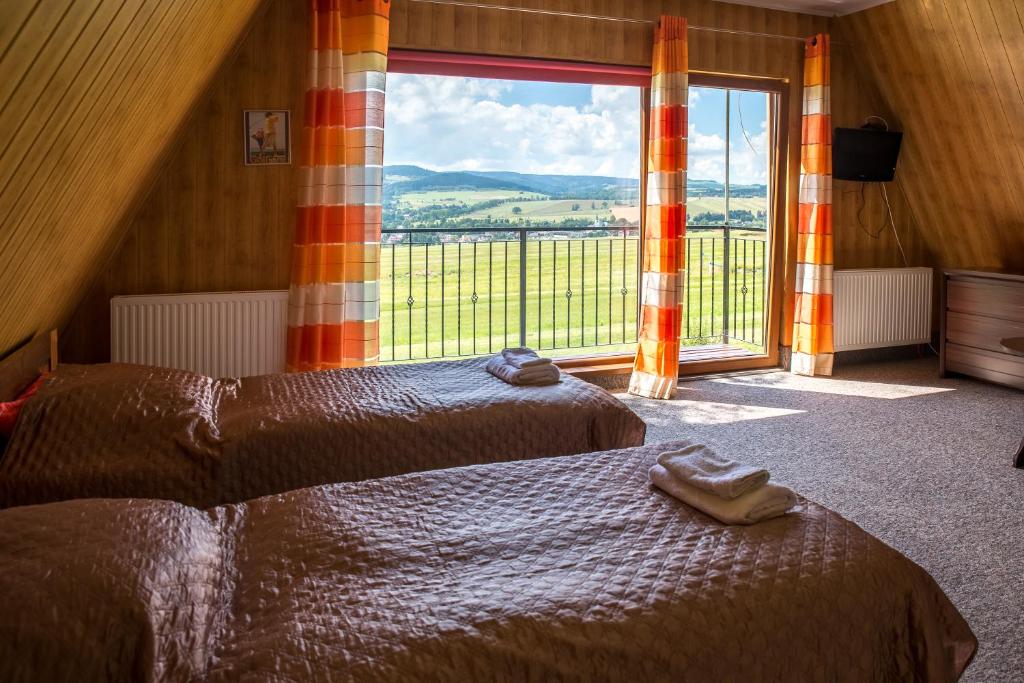 a bedroom with two beds and a large window at GolfSPA Golfowa Wioska in Szczytna