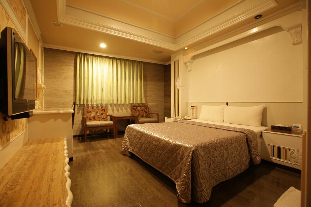een hotelkamer met een bed en een stoel bij Hua Yue Hotel in Taoyuan