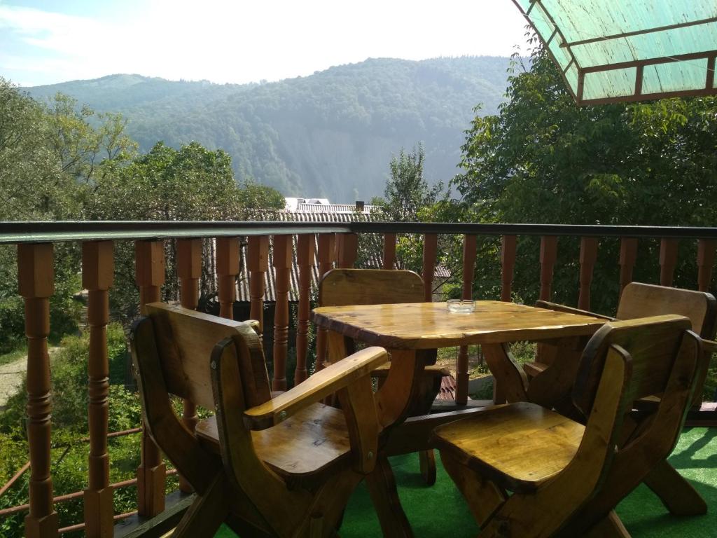 a wooden table and chairs on a balcony with mountains at U dida Grytsya in Yaremche