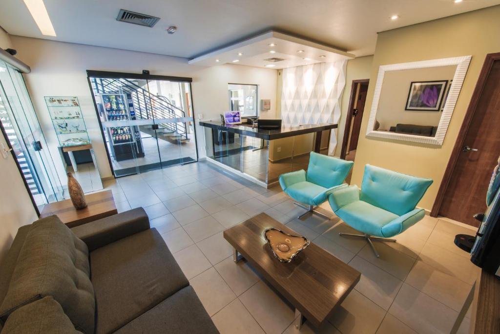 a living room with a couch and blue chairs at Limeira Suítes in Limeira