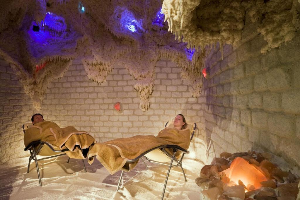two people sitting in chairs next to a fireplace at Ensana Thermal Hévíz in Hévíz