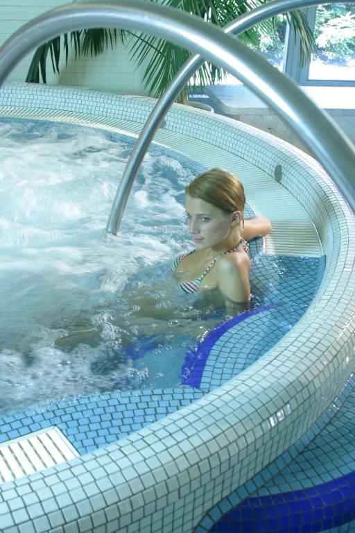 a young girl is sitting in a hot tub at Ensana Thermal Hévíz in Hévíz