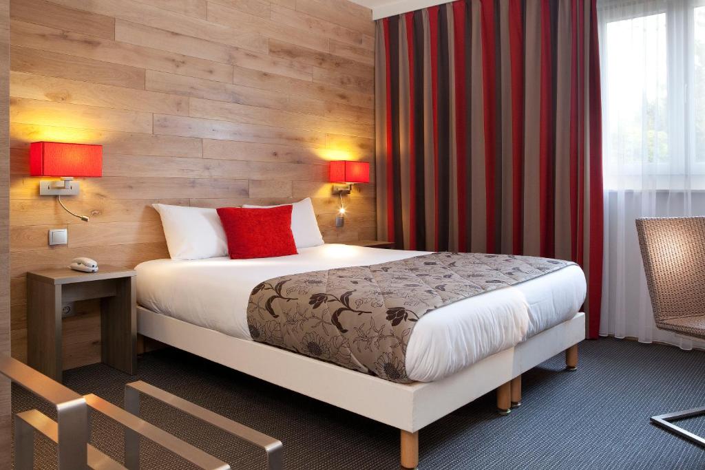 a hotel room with a bed and a desk and red curtains at Hôtel Turenne in Colmar