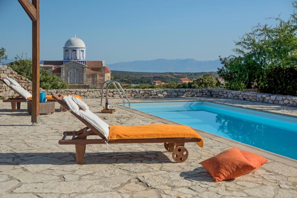 a pool with a lounge chair next to a swimming pool at Villa Cerigo in Aroniadika