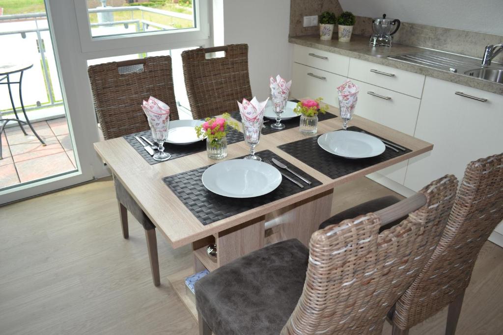 - une table à manger avec des assiettes et des fleurs dans l'établissement Steuerbord, à Horumersiel