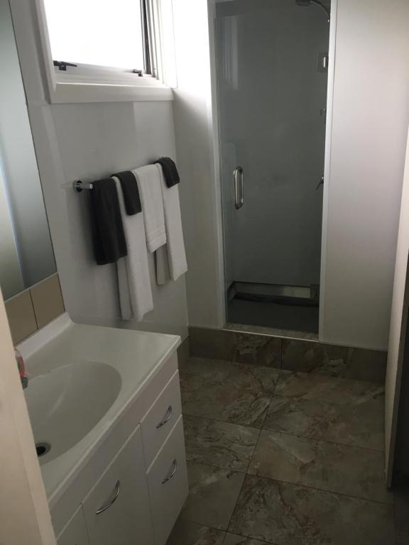 a bathroom with a sink and a shower with towels at Mount View Motel Hawera in Hawera