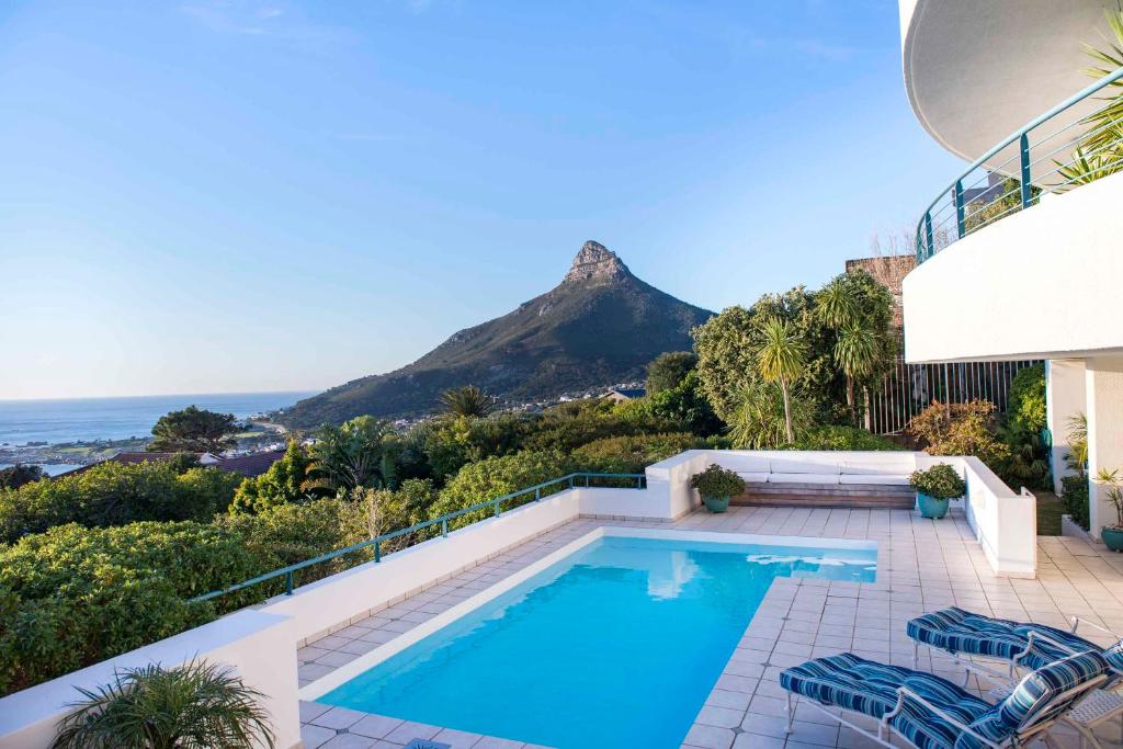 a house with a swimming pool with a mountain in the background at Bay Reflections Camps Bay Luxury Serviced Apartments in Cape Town