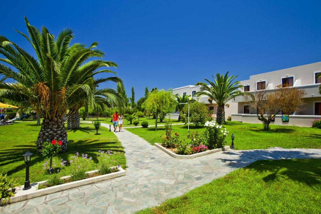 Hotel Esperia في مارماري: حديقة فيها نخيل وزهور ومبنى