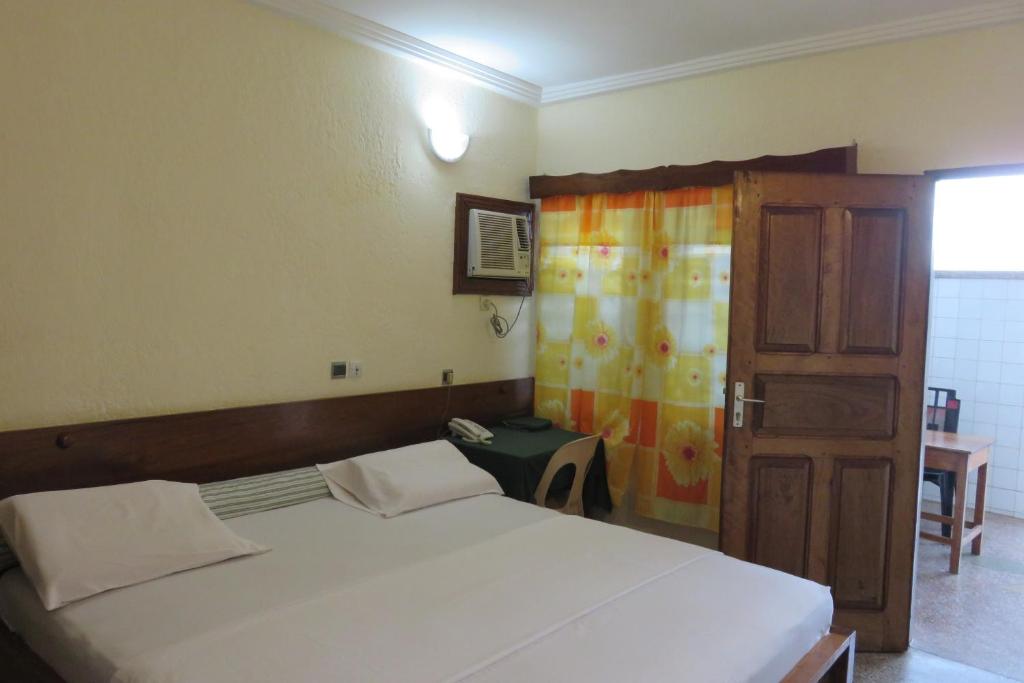 um quarto com uma cama e uma porta de madeira em Hotel Agbeviade em Palimé