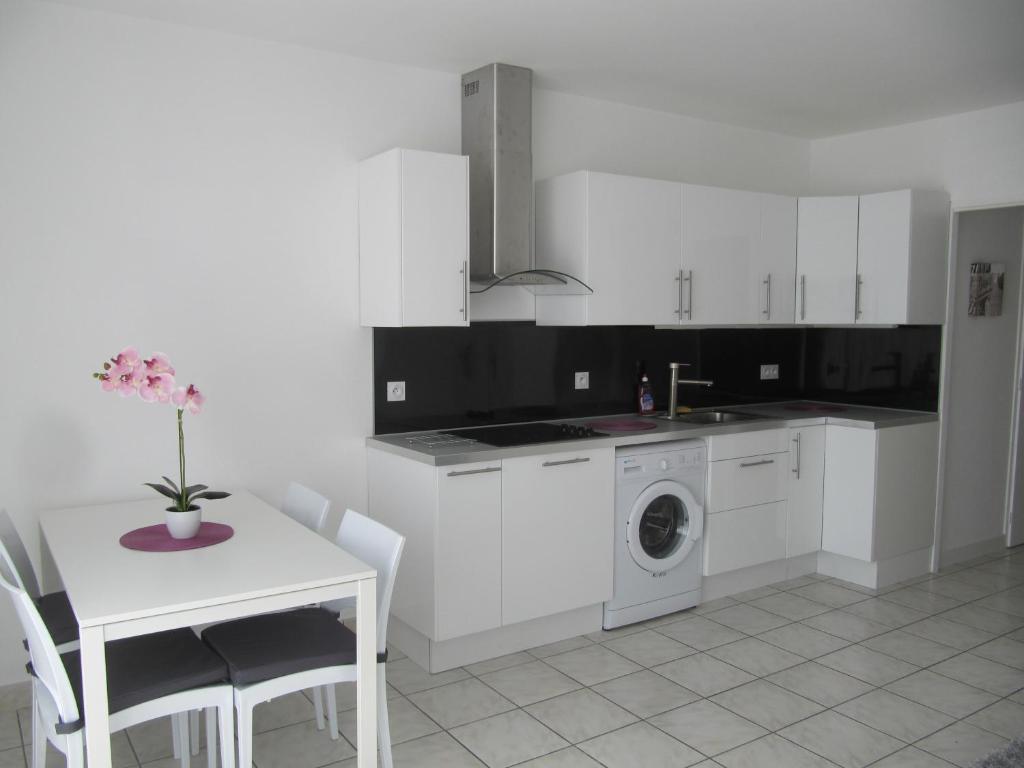 a white kitchen with a table and a washing machine at Clos Saint Médard in Saint-Médard-en-Jalles