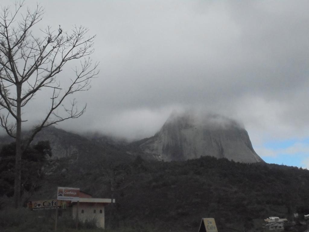 a mountain in the clouds with a building in front of it at Flat 320 in Aracê