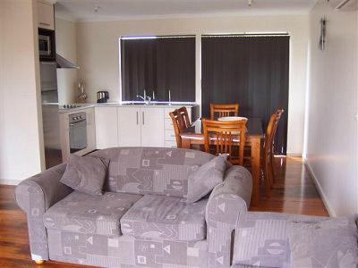 een woonkamer met een bank en een keuken met een tafel bij Glenaire apartments at Pontifex in Strahan