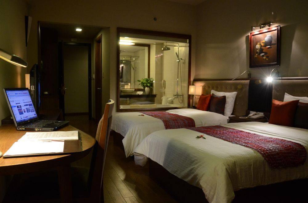 a hotel room with two beds and a laptop on a desk at Asia Hotel Hue in Hue