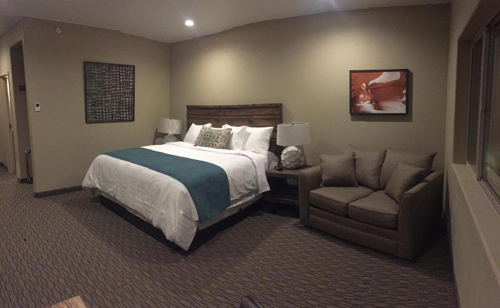a bedroom with a bed and a couch and a chair at Canyon Country Lodge in Escalante