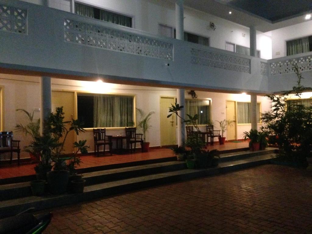 a building with a balcony and tables and chairs at Meya Beach Walk Hotel in Mahabalipuram