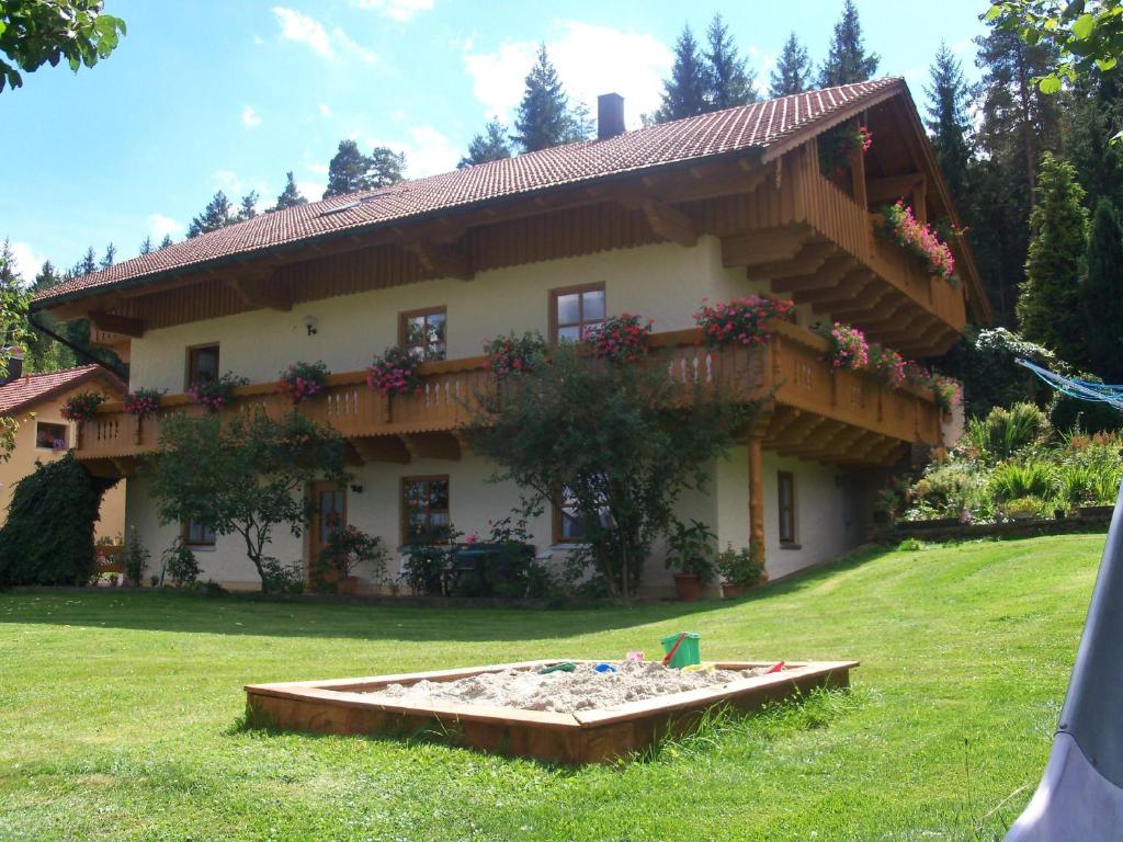 une maison avec un bac à sable devant elle dans l'établissement Ferienwohnung Steinbeisser, à Arrach