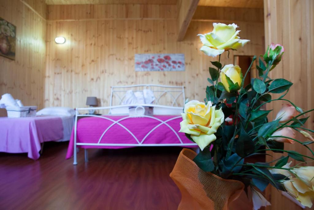 - une chambre avec un lit rose et un vase de fleurs dans l'établissement Acqua di Mare, à Locogrande