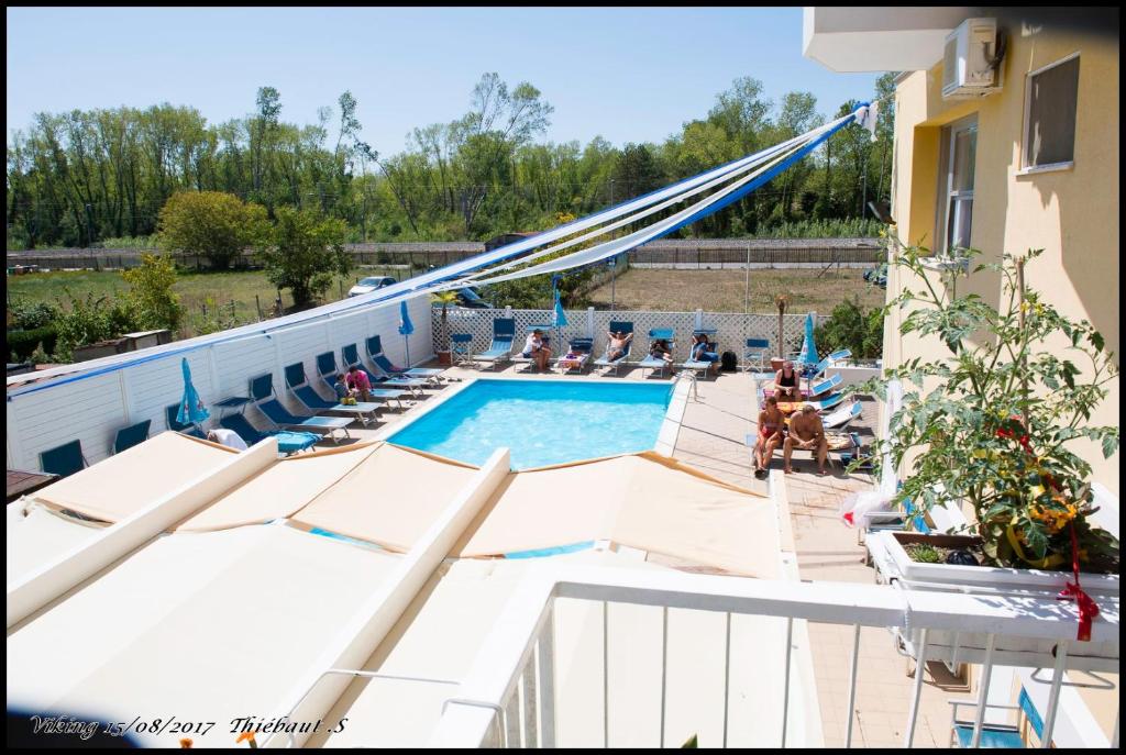 a swimming pool with people sitting in chairs next to a building at Hotel Viking in Rimini