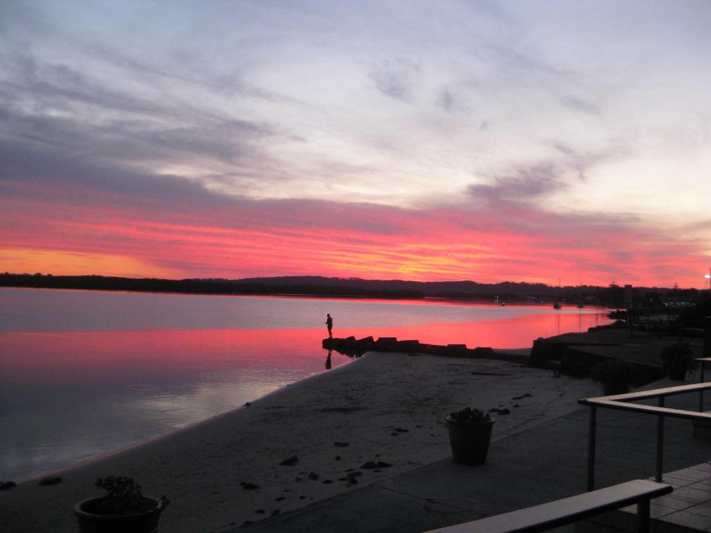 a person standing on the beach at sunset at Villa Riviera on River Front in Ballina