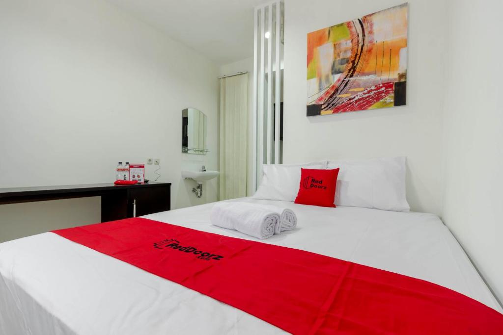 a white bed with a red blanket on top of it at RedDoorz Plus @ Pasar Baru in Jakarta