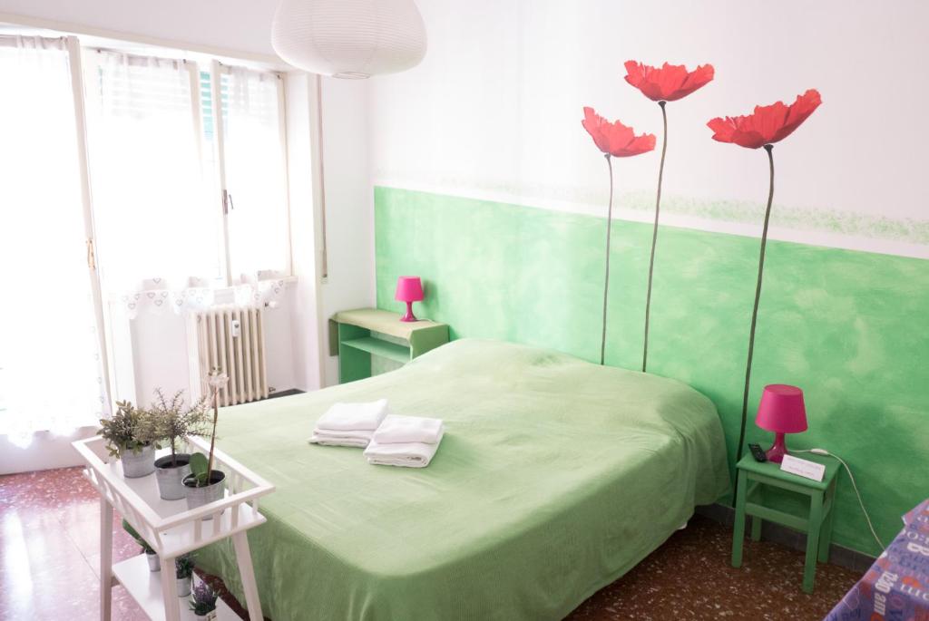 una camera verde con un letto con fiori rosa di Next Stop Affittacamere Casilino a Roma