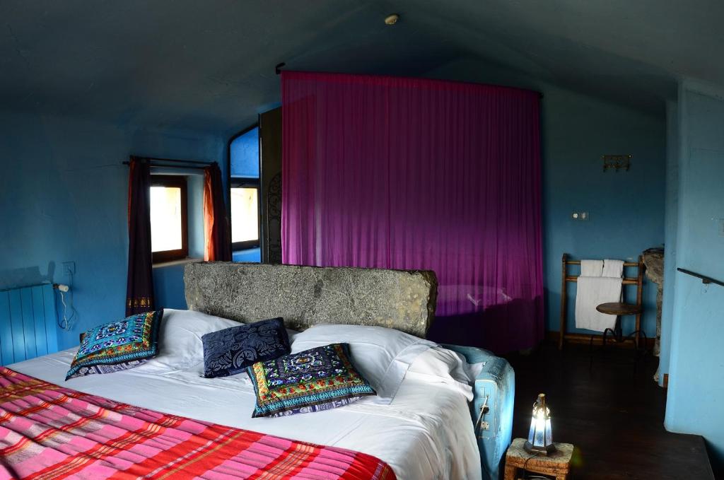1 dormitorio con 1 cama grande y paredes moradas en Hotel Alma de Romero en Carranza