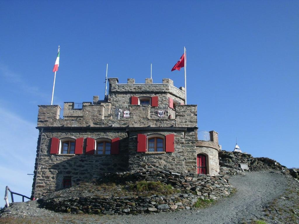 
a stone building with a flag on top of it at Rifugio Garibaldi in Passo Stelvio
