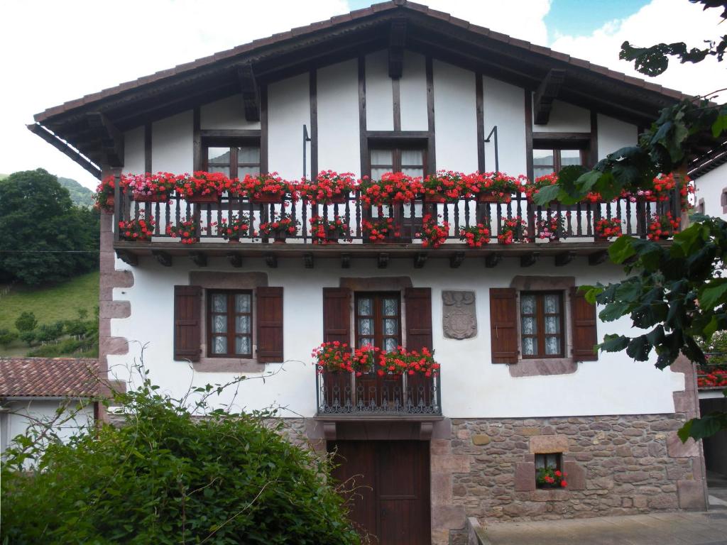 Casa blanca con flores rojas en los balcones en Casa Rural Bordaberea, en Maya del Baztán