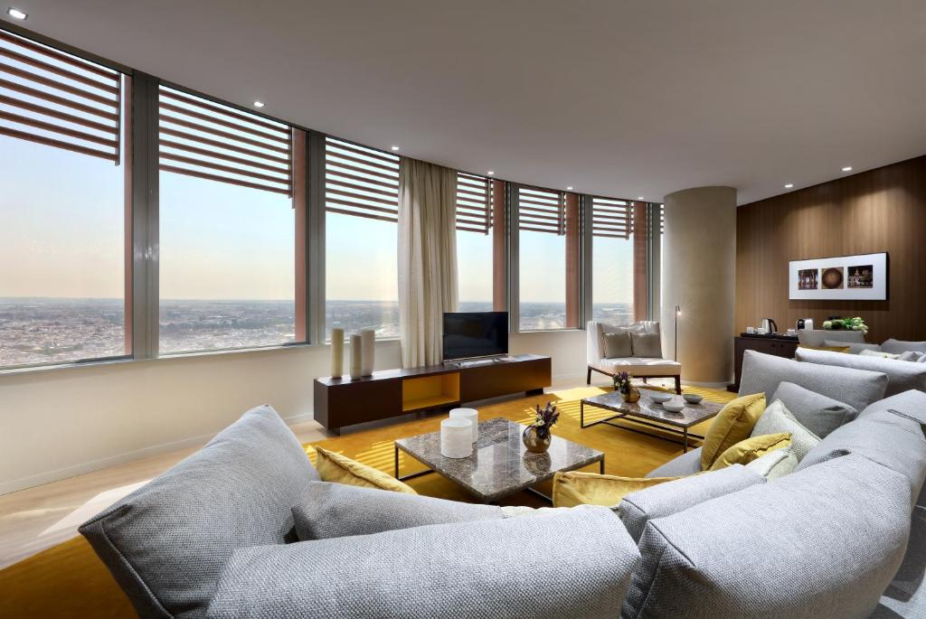 a living room with couches and a tv and windows at Eurostars Torre Sevilla in Seville