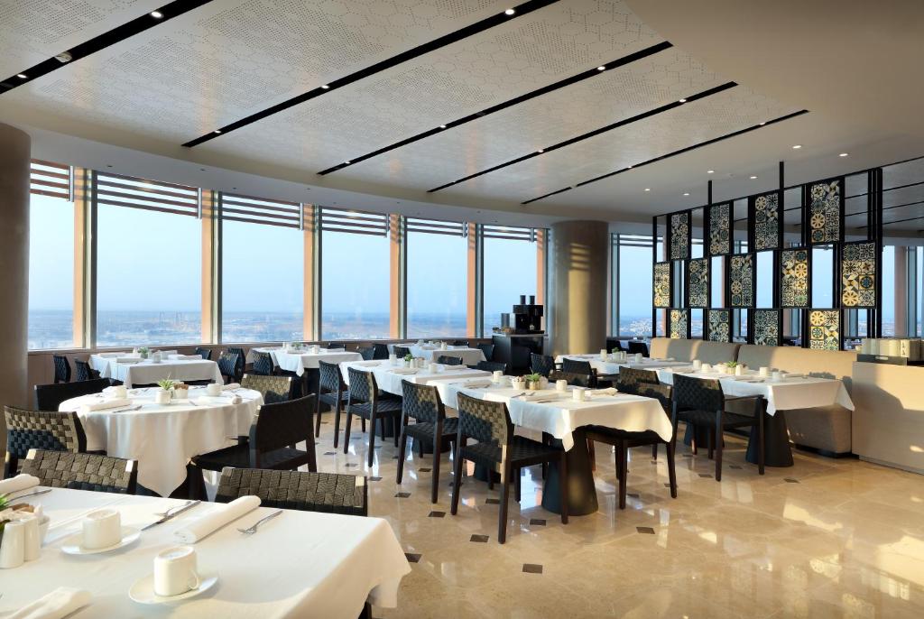 a restaurant with white tables and chairs and windows at Eurostars Torre Sevilla in Seville