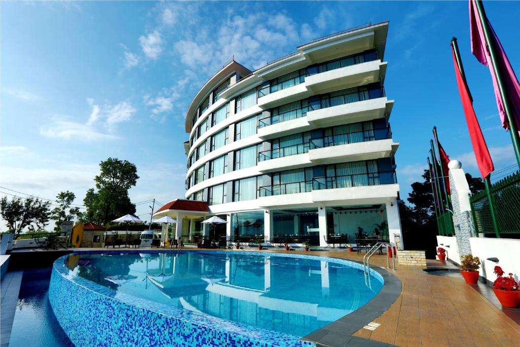 a hotel with a swimming pool in front of a building at Himalayan Front Hotel by KGH Group in Pokhara