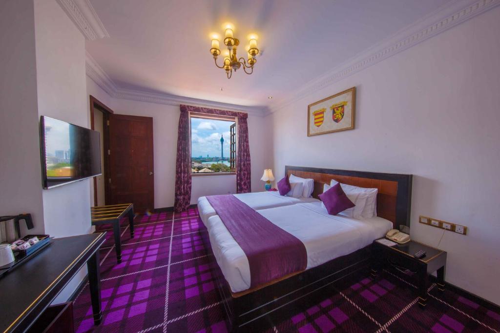 コロンボにあるスチュアート バイ シトラスの大きなベッドとシャンデリアが備わるホテルルームです。